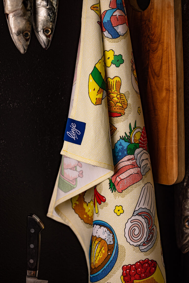 Illustration by Nicolas Ridou: Tea towel illustrated with colorful culinary motifs, hung near kitchen utensils for Linje